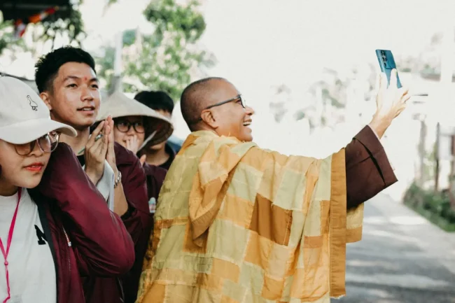 A Buddhist monk using a phone to take a selfie of himself and another monk.